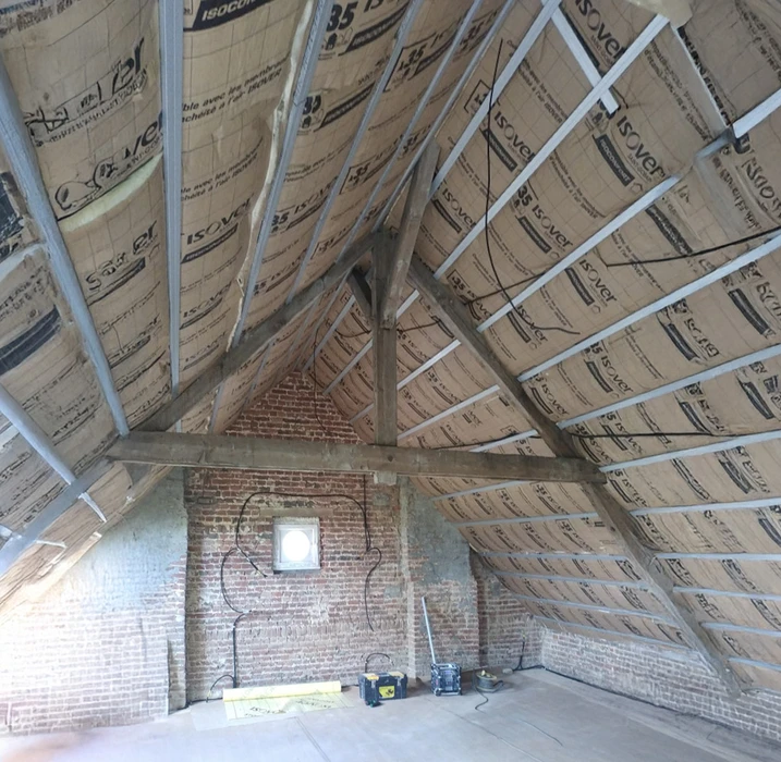 Chantier de rénovation dans combles avec cheminée en briques rouges apparentes