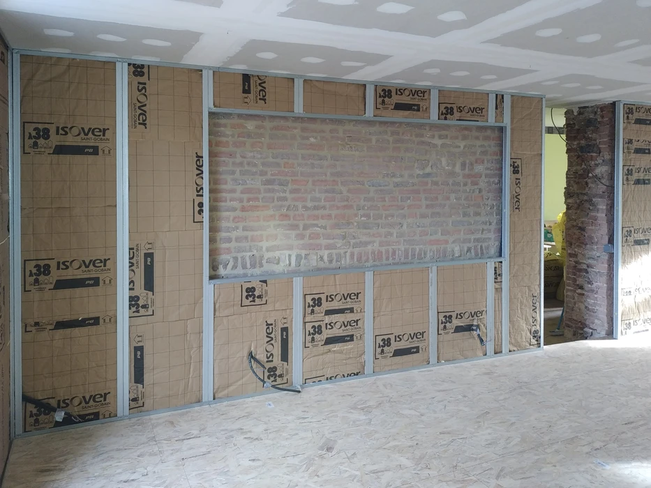 Chantier de rénovation intérieure avec ouvrier installant l'isolation thermique