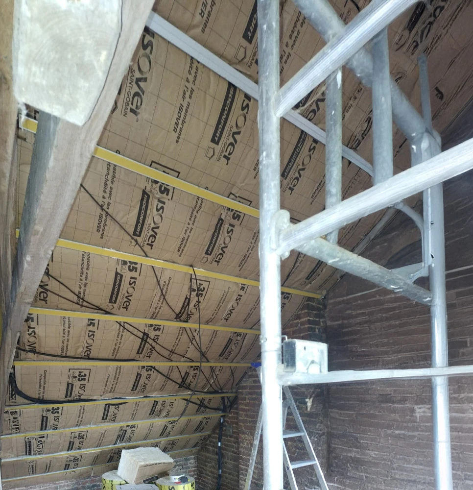 Chantier de construction intérieur montrant l'installation d'une charpente métallique avec poutres en acier galvanisé