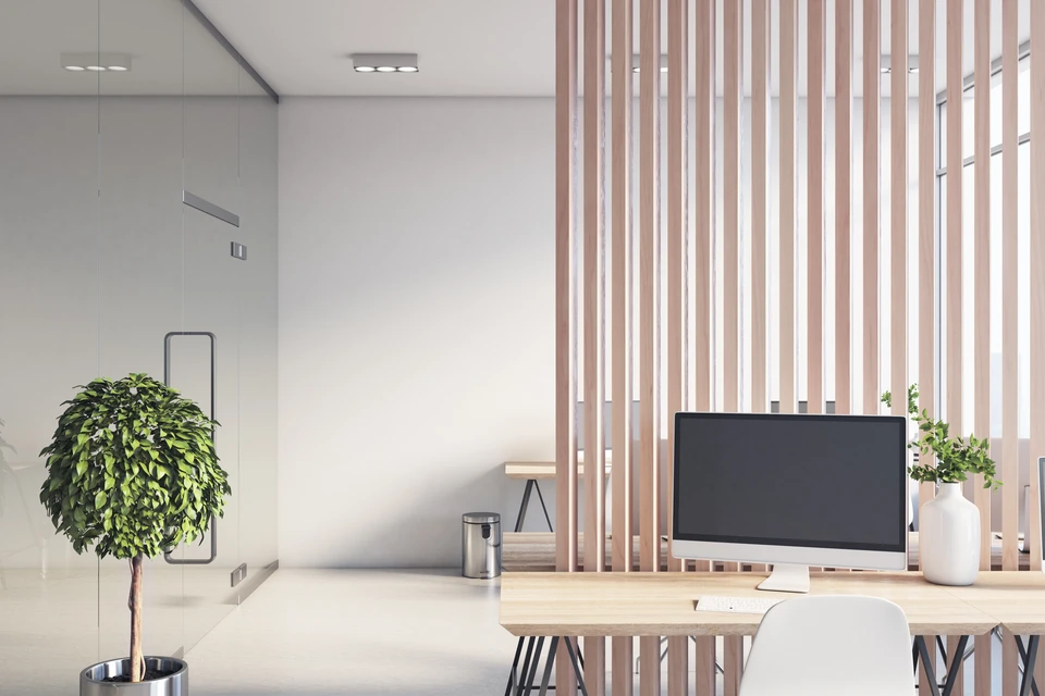 Salle de bureau design et ensoleillée avec cloison en bois entre rangées de lieux de travail, mur transparent en verre, ordinateurs modernes et tables en bois