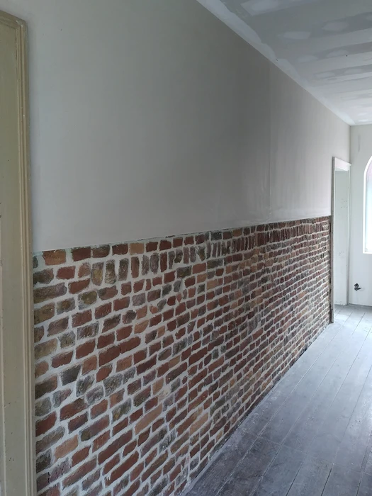 Chantier de rénovation intérieure avec ouvrier installant l'isolation thermique