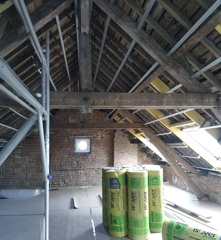 Salon moderne sous combles avec poutres apparentes en bois massif, grandes verrières zénithales